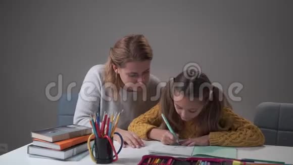 可爱的高加索母亲给她可爱的聪明女儿五个帮助聪明的女学生做家庭作业的女人视频的预览图