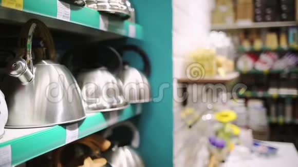 商店和商店一位年轻漂亮的黑发女人在家庭用品部挑选茶壶视频的预览图