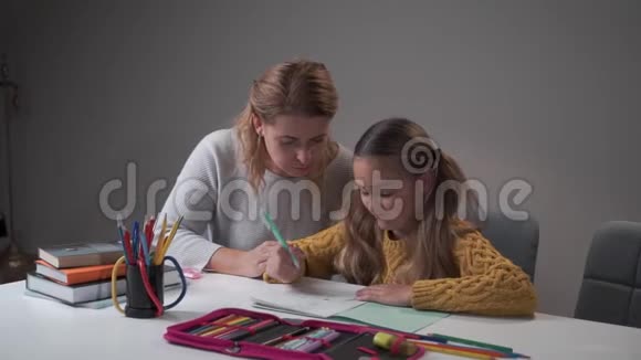 漂亮的白种人女学生在练习本上写字做错误和扔笔想让她平静下来的女人视频的预览图