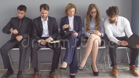 一群失业的人期望在办公楼走廊的椅子上接受采访视频的预览图