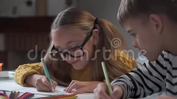 两个白人孩子做家庭作业的特写戴眼镜的女孩注意到她哥哥在作弊穿条纹衣服的男孩视频的预览图