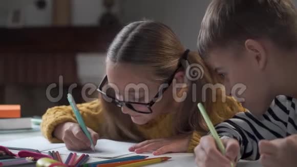穿条纹夹克的白种人男孩的特写镜头看着他姐姐或同学的练习本女孩视频的预览图