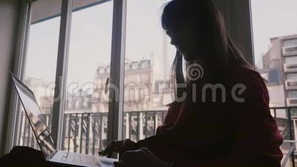 美丽优雅的年轻女商人使用笔记本电脑在房间窗口与埃菲尔铁塔景在巴黎出差视频的预览图