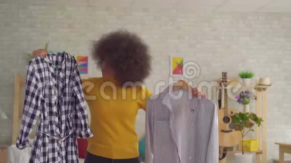 一个非洲女人留着非洲发型在他现代公寓的镜子前试穿衣服视频的预览图