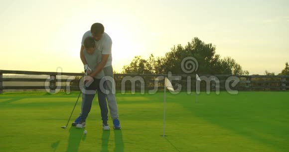 一个人和他的儿子在夏天的完美高尔夫球场打高尔夫球视频的预览图