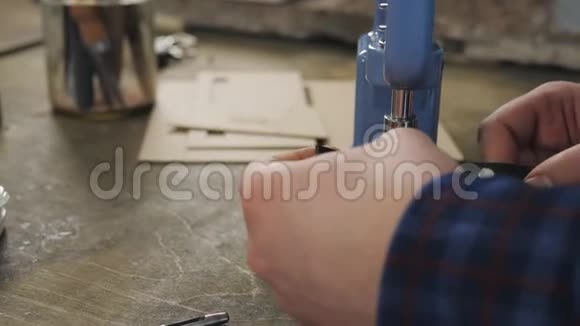 男工使用压力机在真皮产品上安装金属小孔关闭4k视频的预览图