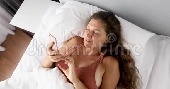 床上的女人看电话视频的预览图