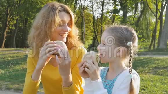 年轻的母亲和小女儿在周末在公园里吃快餐不健康视频的预览图