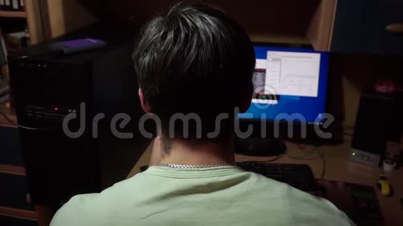 后脑勺黑头发的年轻人坐着电脑移动他的手老鼠视频的预览图