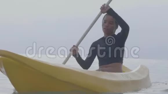 结束无忧无虑的年轻女人在宁静的海洋中划桨和皮划艇视频的预览图