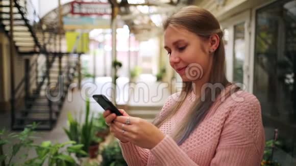 互联网和社交网络一位年轻漂亮的金发女郎在购物亭的社交网络上交流视频的预览图