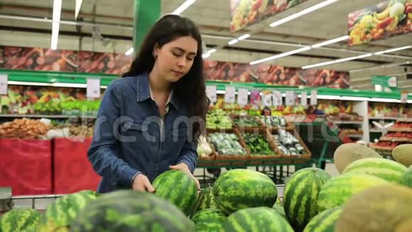 在超市购物年轻的美女在水果店的货架上摘西瓜视频的预览图