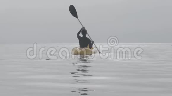 一个女人在平静开阔的海洋中划桨后景视频的预览图