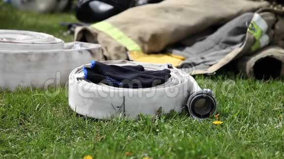 消防水管躺在草地上手套和夹克的特写视频的预览图