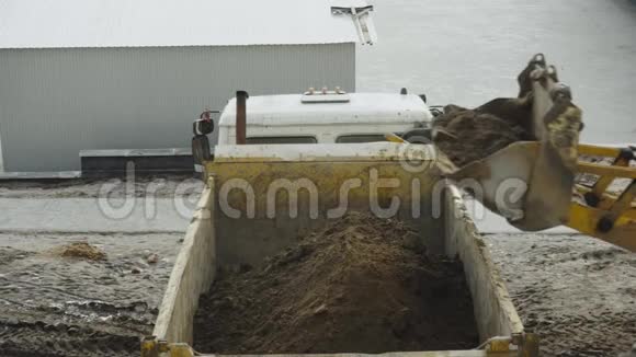 挖掘机在建筑物中将沙子倒入自卸卡车的壳体中从顶部拍摄的视图工程视频的预览图