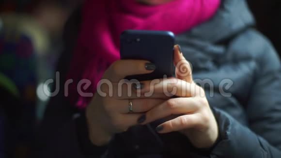 一位乘坐公共交通工具的妇女手里拿着智能手机视频的预览图