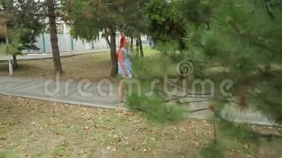 一个女人在公园里沿着绿色的小巷散步视频的预览图