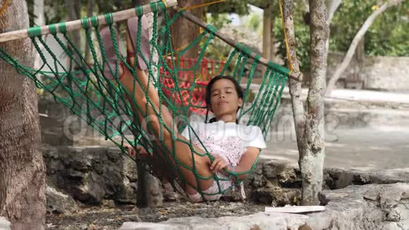 夏天一个度假胜地一个美丽的女人睡在树下的吊床上视频的预览图