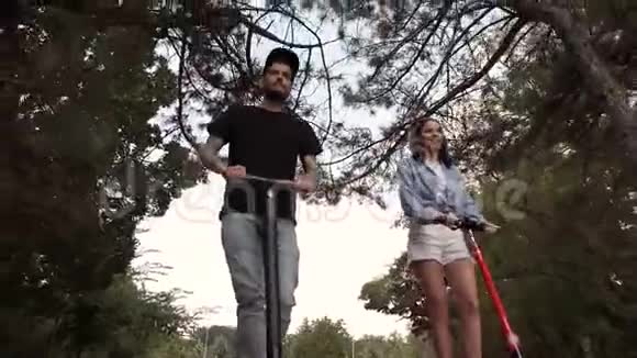 女孩和她的男朋友在大自然中骑着一辆电动滑板车彼此交谈视频的预览图