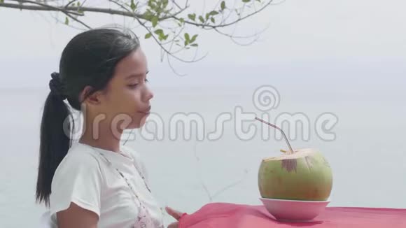 一位亚洲女人喝新鲜椰子汁的户外特写夏季肖像视频的预览图