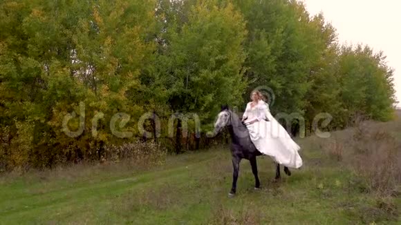 穿着白色礼服的漂亮未婚妻正骑着马沿林而行视频的预览图