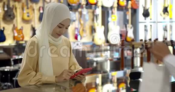 年轻的穆斯林妇女使用智能手表支付非接触式交易出纳柜台视频的预览图