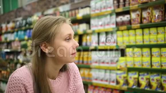 在超市购物一个年轻漂亮的女人看着商店里的货架甜甜地笑着视频的预览图