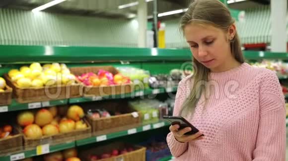一家超市和一部手机年轻的美女在商店购物时使用手机视频的预览图
