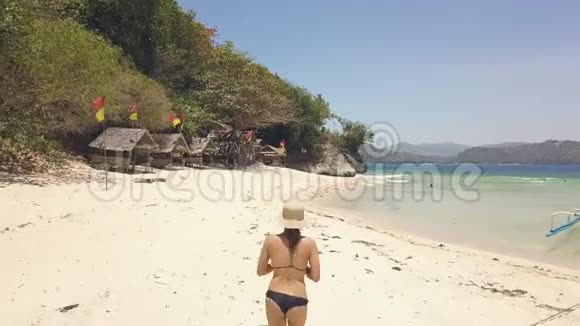 穿比基尼的女游客正在岛上的沙滩上奔跑后景视频的预览图
