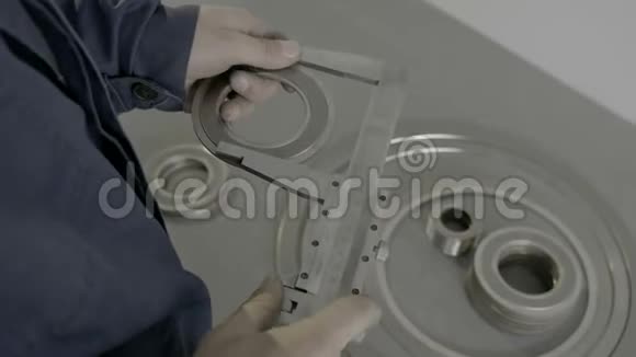 一个熟练的蓝色工人测量一个零件的尺寸使用游标卡尺在工厂视频的预览图