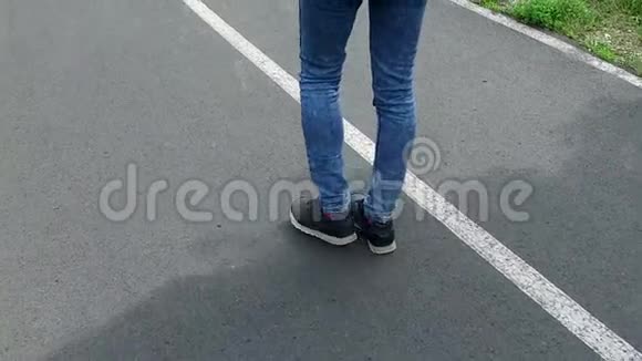 年轻女子穿着运动鞋和牛仔裤在户外小路上的特写视频的预览图