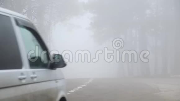 汽车在森林里浓雾中驶过道路能见度低的概念视频的预览图