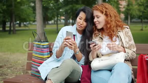 快乐的女孩在公园的长椅上玩智能手机聊天视频的预览图