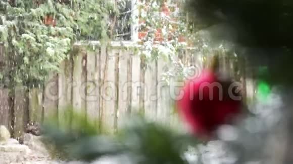 模糊的红色圣诞树玩具挂在窗户背景上的圣诞树上外面可见下雪视频的预览图