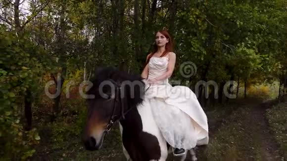 穿米色连衣裙的红头发女正在骑马关门视频的预览图