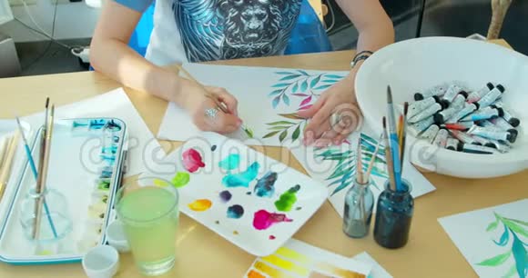 画家手里拿着画笔水彩画花和艺术设备在桌子上顶部视图视频的预览图