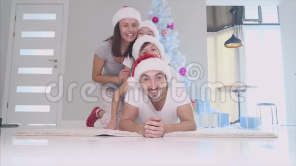 两个兄弟姐妹和父母在胡闹父亲在地毯上拉儿子在父亲背上女儿在上面视频的预览图