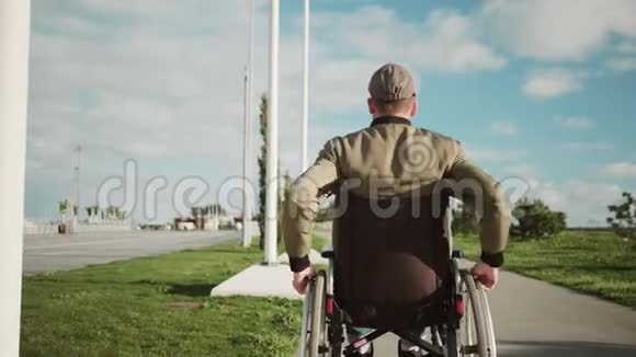 男性轮椅使用者独自行走在街道上转动轮子后视视频的预览图