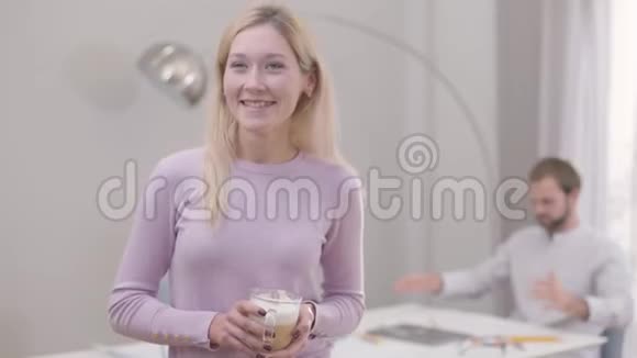 年轻微笑的白种人女人喝卡布奇诺或拿铁作为留胡子的男人在后台工作专业人员视频的预览图