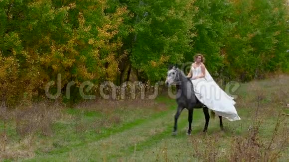 穿着白色衣服的漂亮女孩骑着马走林视频的预览图