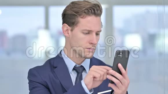 悲伤的年轻商人在智能手机上吃亏的画像视频的预览图