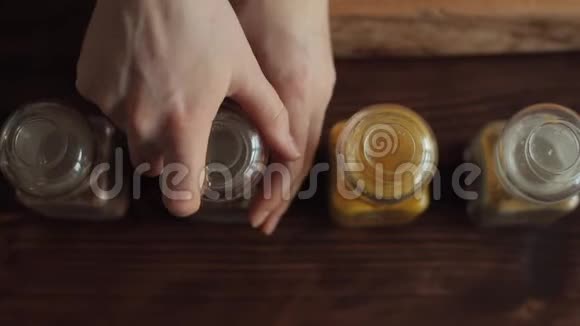 一个年轻女孩的手特写打开一个玻璃罐子的香料用一个小勺子把它们拉出来从这里看视频的预览图