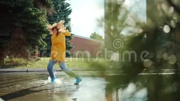 穿着雨衣的学生穿着耳机听音乐的胶靴在水坑里跳视频的预览图