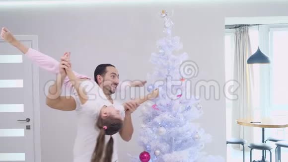 活泼的父亲和他运动的女儿在父亲肩膀上的分裂位置正在一起装饰杉树视频的预览图