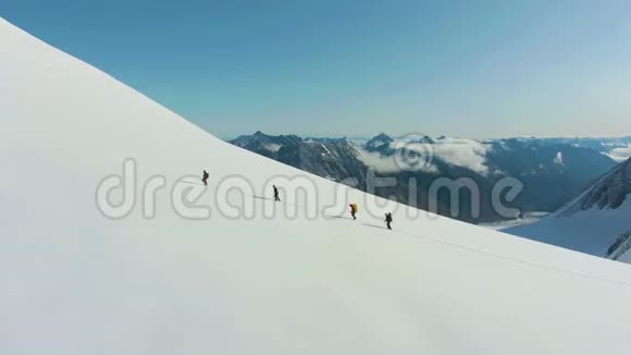 一群登山队员正在雪山上作为一个骑自行车的队伍前进鸟瞰图视频的预览图