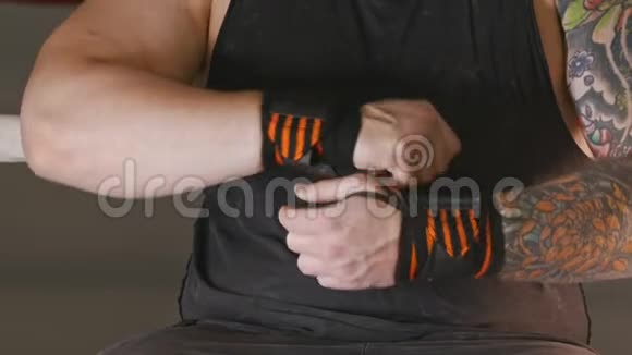 一个肌肉发达的男人手腕上有黑色和橙色条纹的弹力绷带视频的预览图