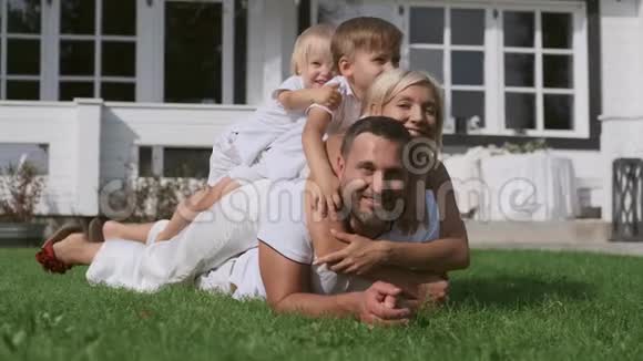 幸福的家庭孩子们玩得开心躺在草地上的房子附近视频的预览图