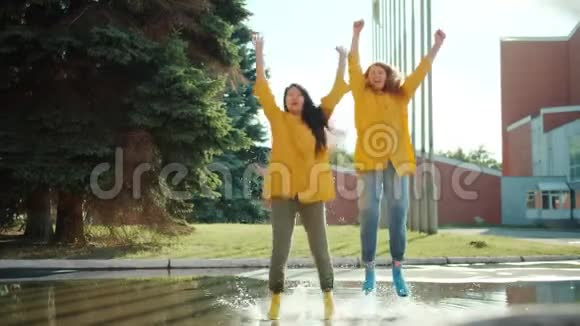快乐的年轻女性在水坑里跳到户外举起手臂享受乐趣的肖像视频的预览图