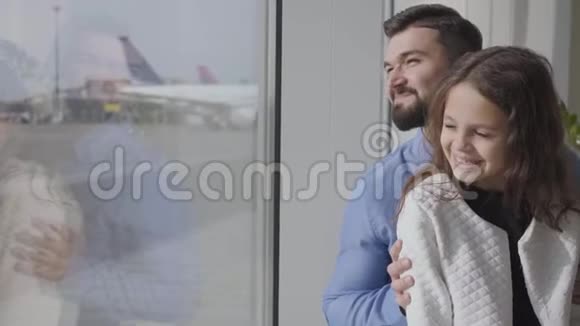 一个快乐的白人男人和他的女儿坐在机场窗台上看着跑道小可爱视频的预览图