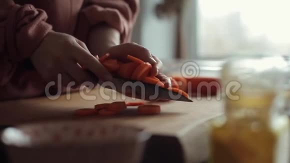 在厨房桌上的一个大碗里堆着切碎的胡萝卜的年轻女人的手视频的预览图